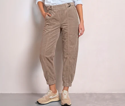 Personne portant un pantalon en velours côtelé Street One beige avec boucle en D et taille élastique, une main dans la poche, avec des baskets claires.
