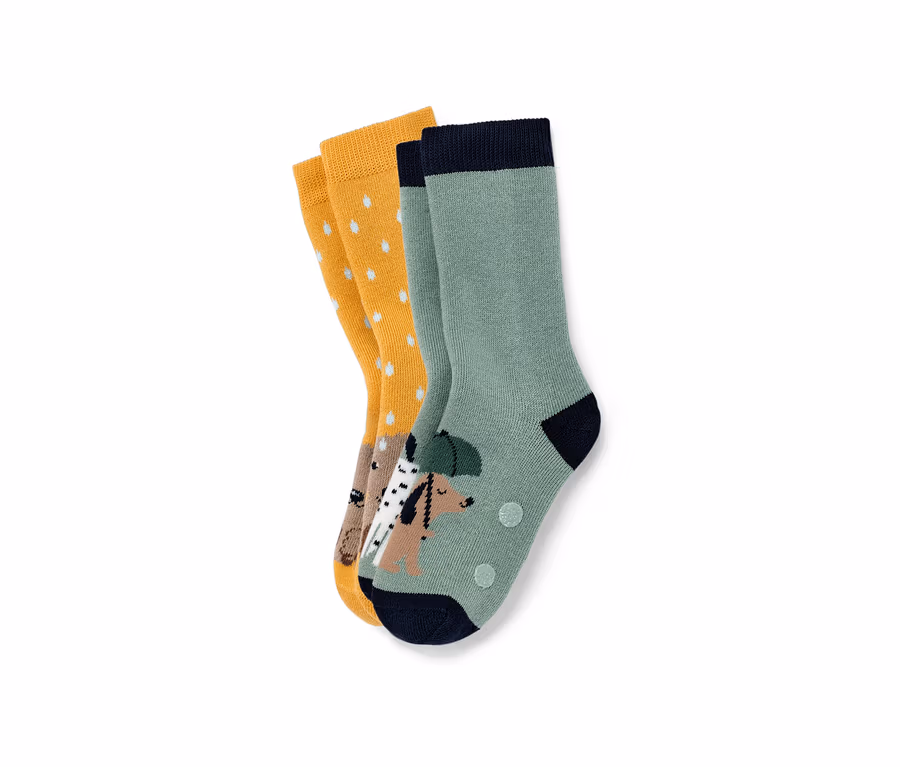 Deux paires de chaussettes anti-dérapantes pour enfant : une paire moutarde à pois blancs et une paire verte avec un motif de chien.