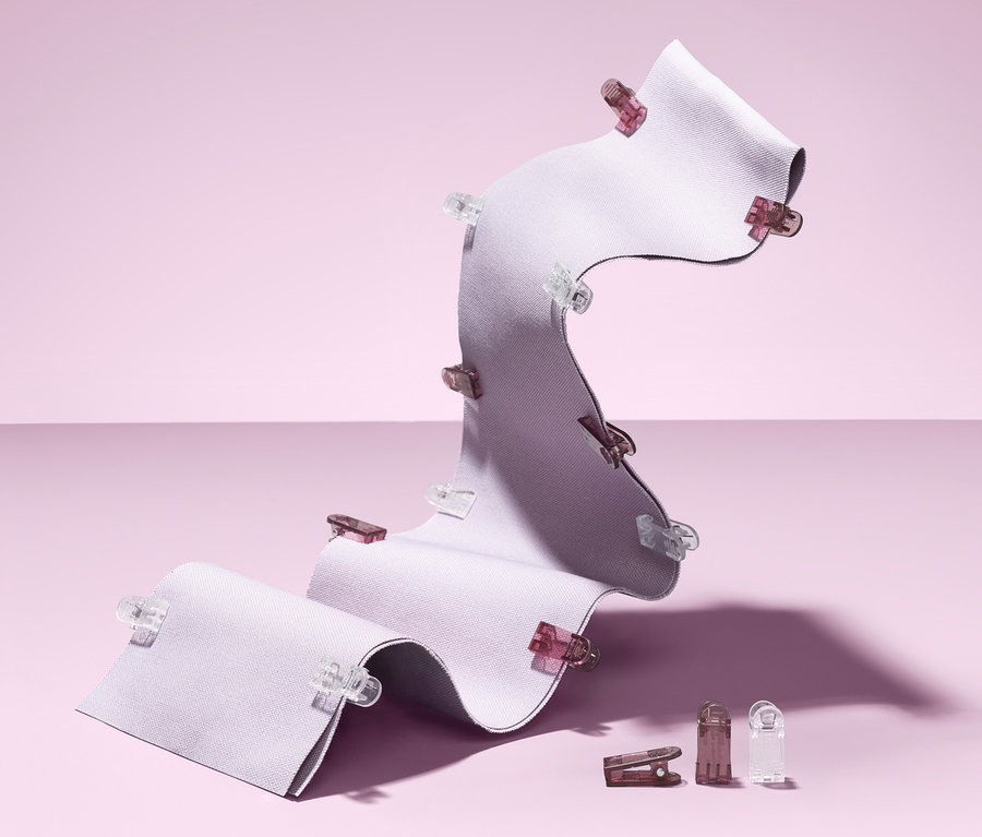 Un morceau de tissu blanc ondulé est fixé par 20 pinces à tissu.