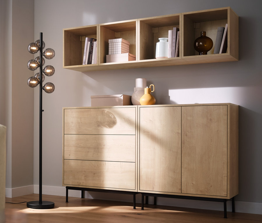 Salon avec canapé, lampadaire « globes en verre » et étagères modulables « Flemming » aspect chêne.