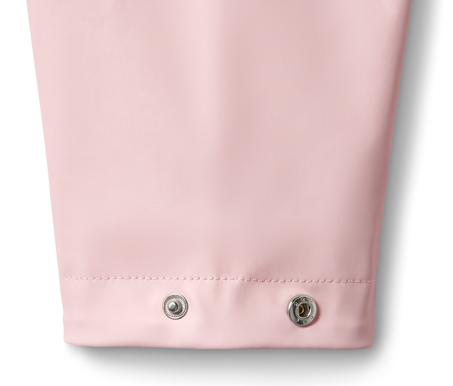 Gros plan sur une parka de pluie rose avec deux boutons-pression argentés.