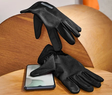 Deux gants de course noirs posés sur une table en bois à côté d'un téléphone portable.