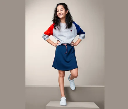 Fillette posant dans une jupe sportive en jersey bleue.