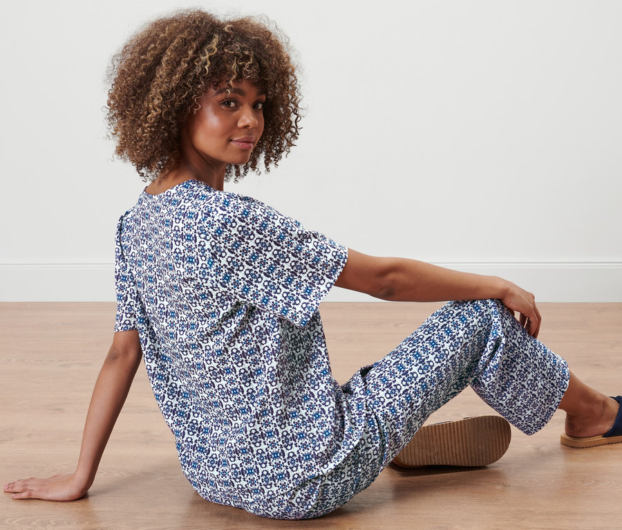 Femme assise par terre portant une blouse à imprimé intégral et un pantalon.