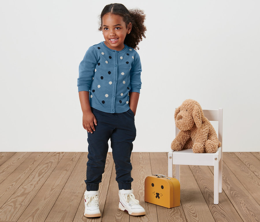 Une fille porte une veste en maille pour tout-petit.