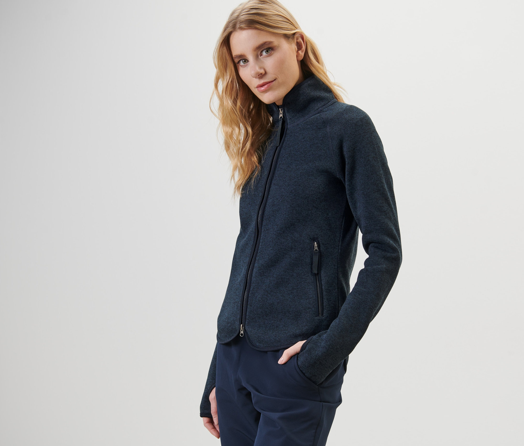 Femme posant en veste en maille polaire bleu foncé.