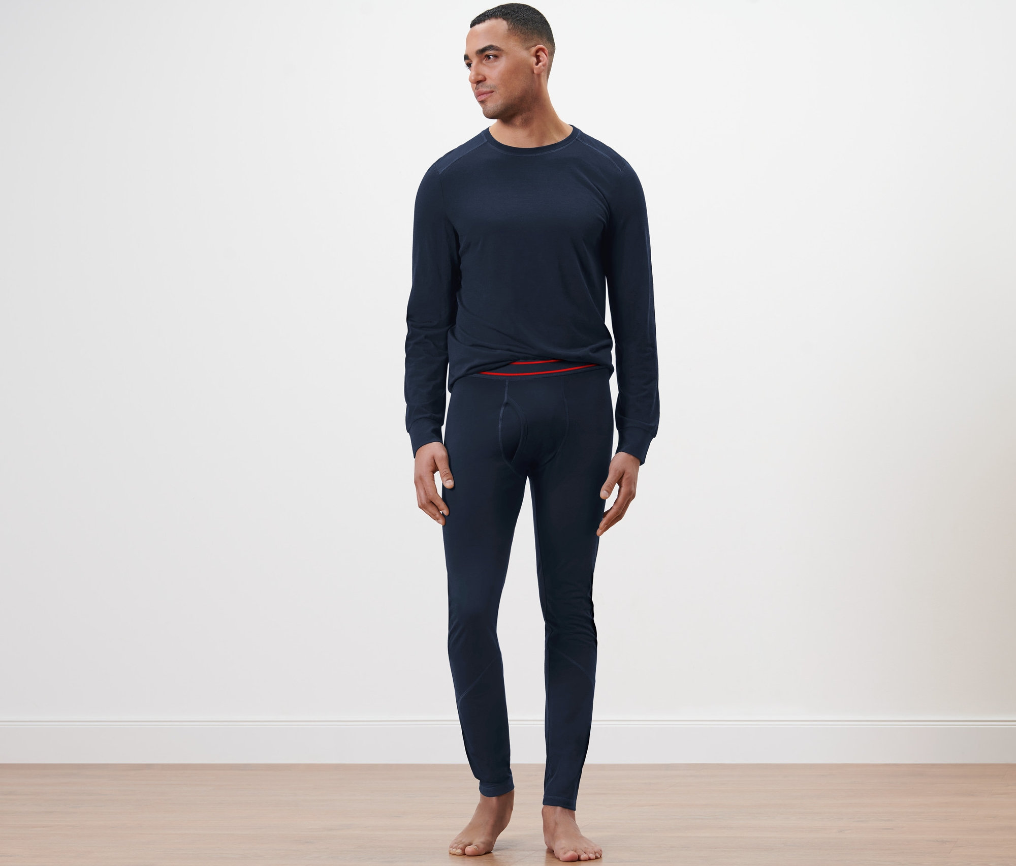 Un homme debout portant un caleçon long en laine certifiée RWS bleu marine.