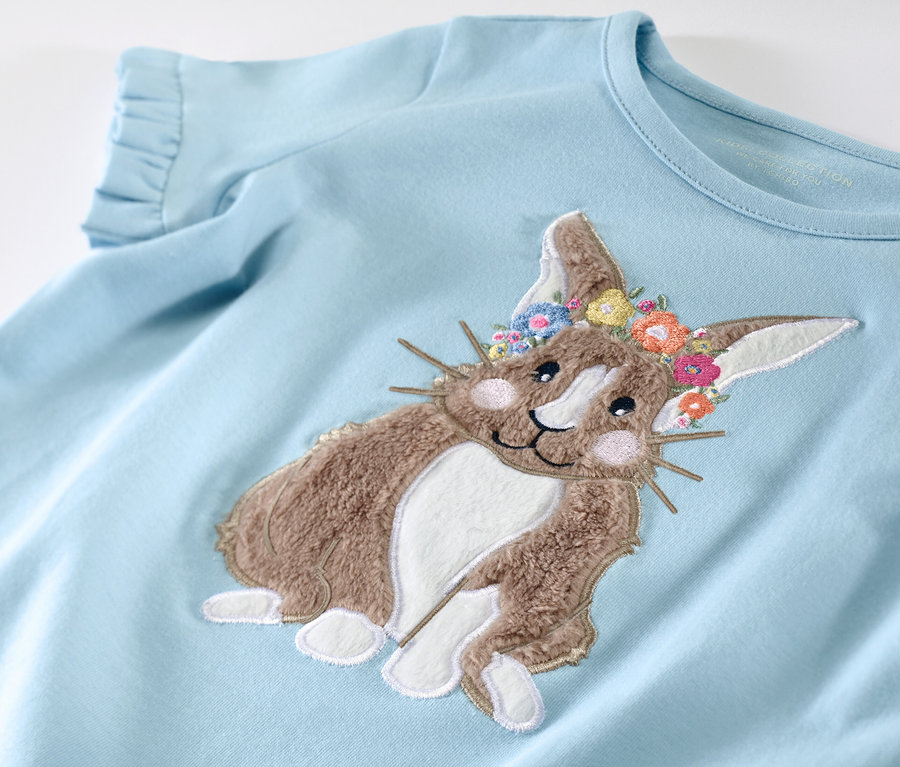 T-shirt bleu clair pour enfant avec un motif de lapin et une couronne de fleurs.