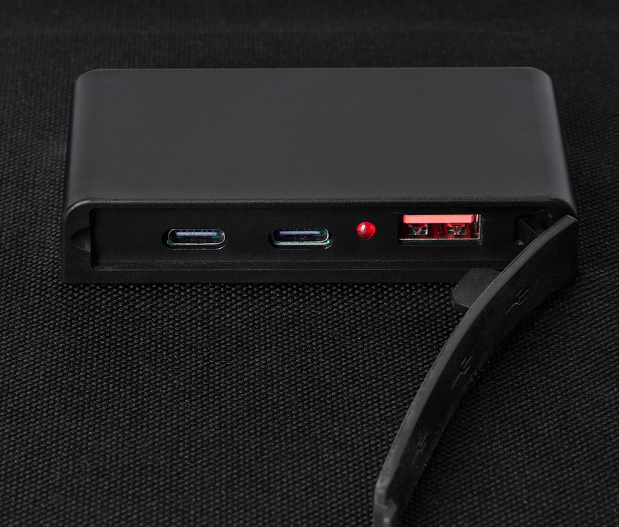 Un chargeur solaire pliable noir de 10 W sur une surface textile noire.