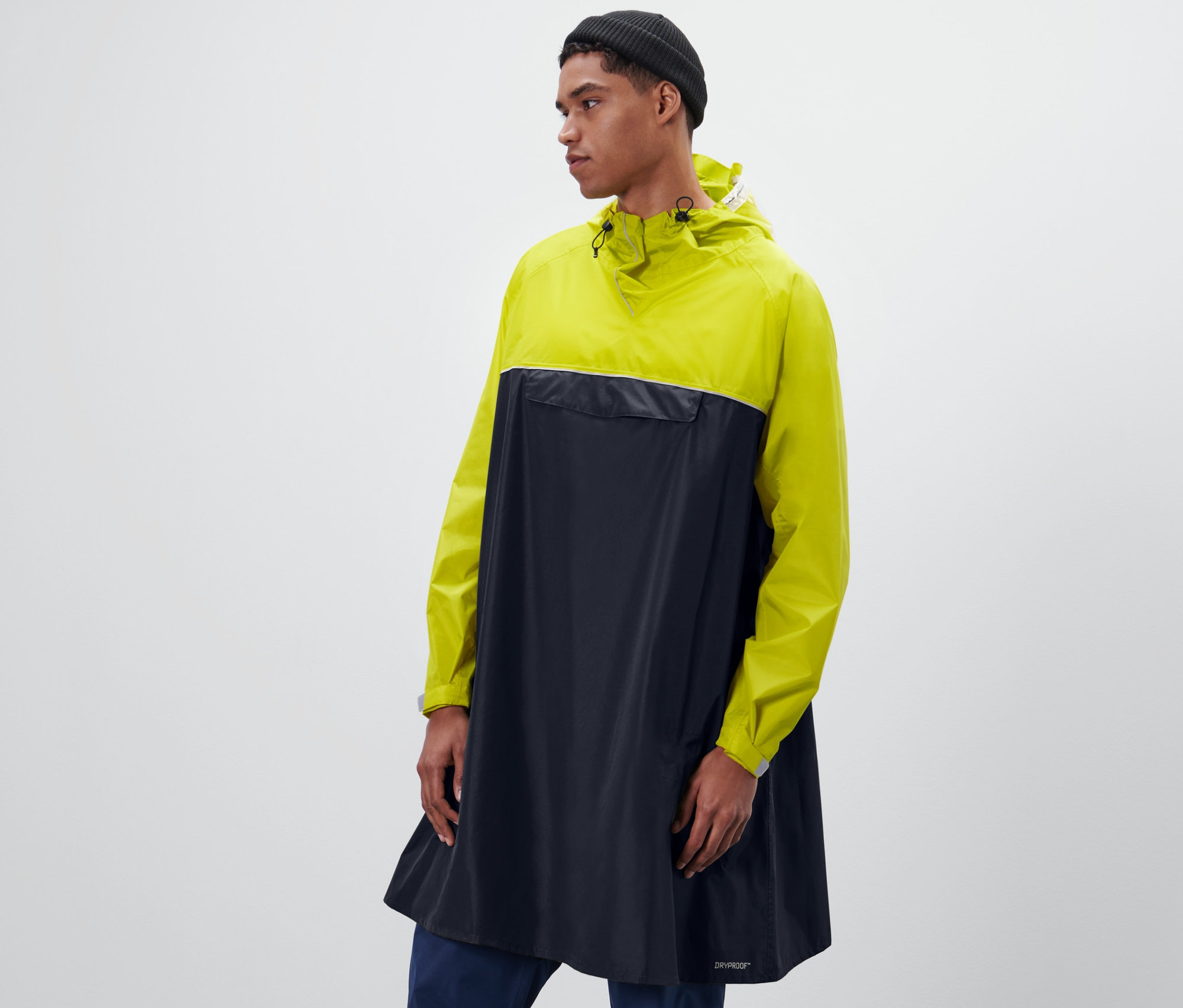 Un homme portant un bonnet noir porte un poncho de pluie jaune et bleu marine à manches.
