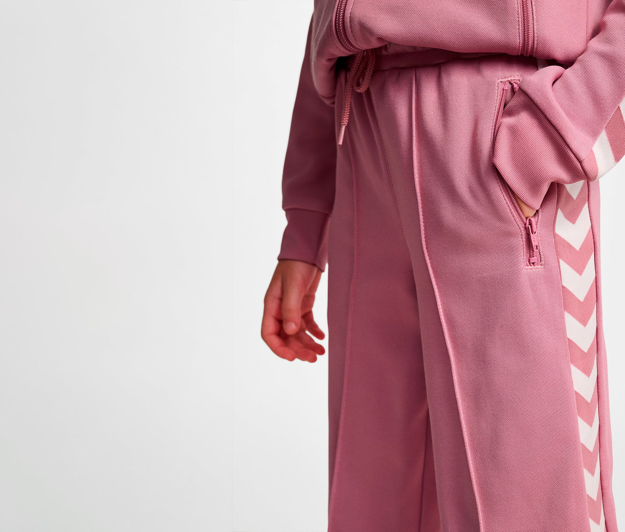 Une personne a une main dans la poche du pantalon large HUMMEL HMLJR Archive Poly.