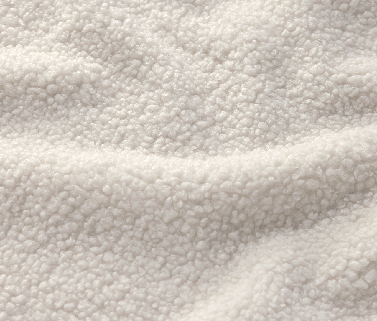 Gros plan d'un tissu blanc crème avec une texture sherpa.