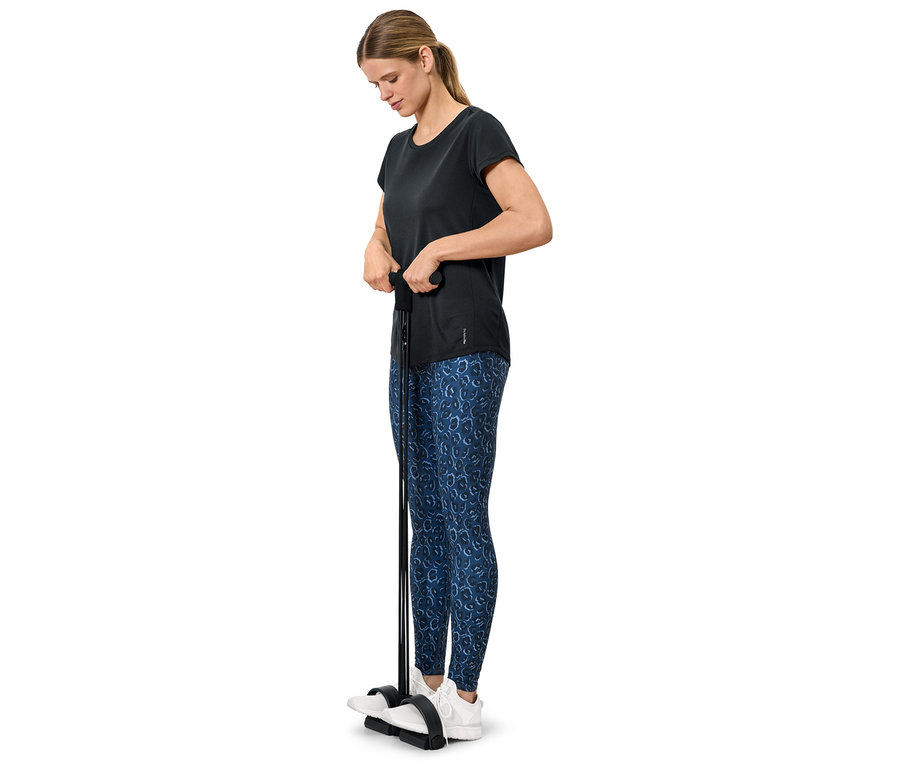 Femme faisant de l'exercice avec un appareil de fitness, elle porte un t-shirt noir et un legging bleu.