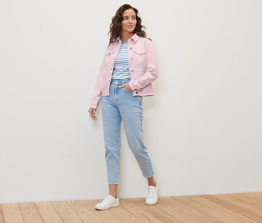 Femme posant en veste en jean rose et jean bleu clair.