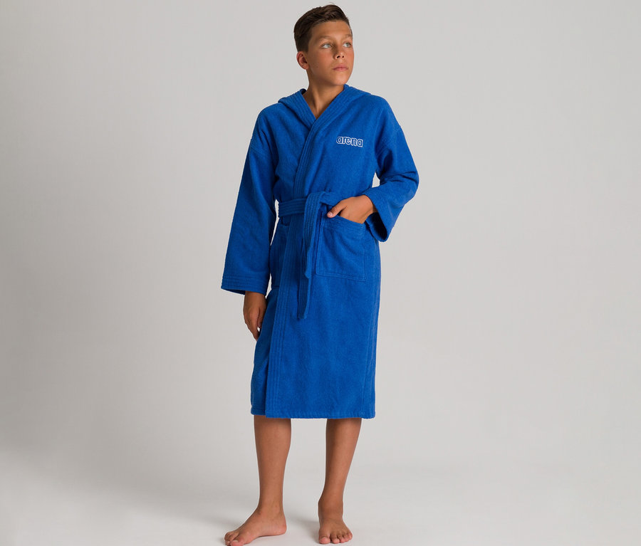 Garçon portant un peignoir à capuche bleu Peignoir pour enfant arena Zeppelin Light JR, debout pieds nus, une main dans la poche.