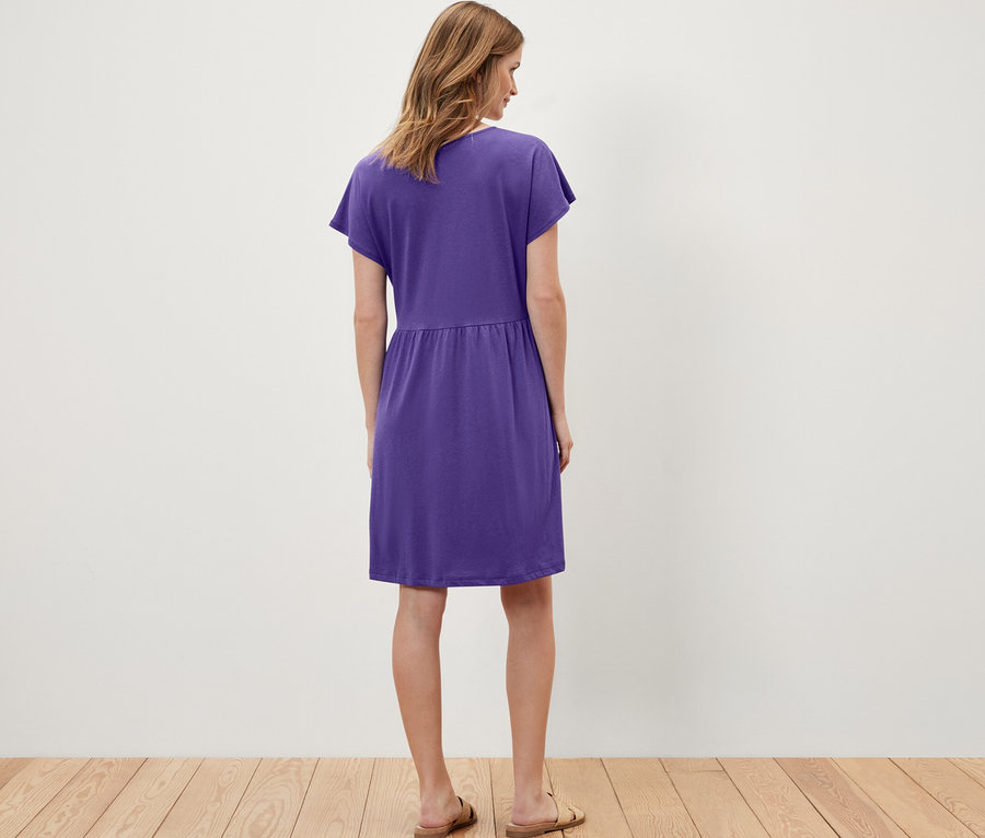 Une femme porte une robe en jersey violette.