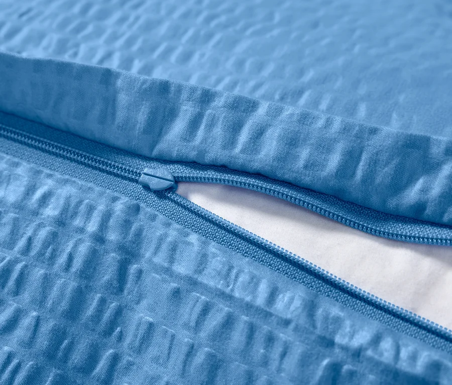 Gros plan d'une housse de couette en seersucker bleue avec fermeture éclair.
