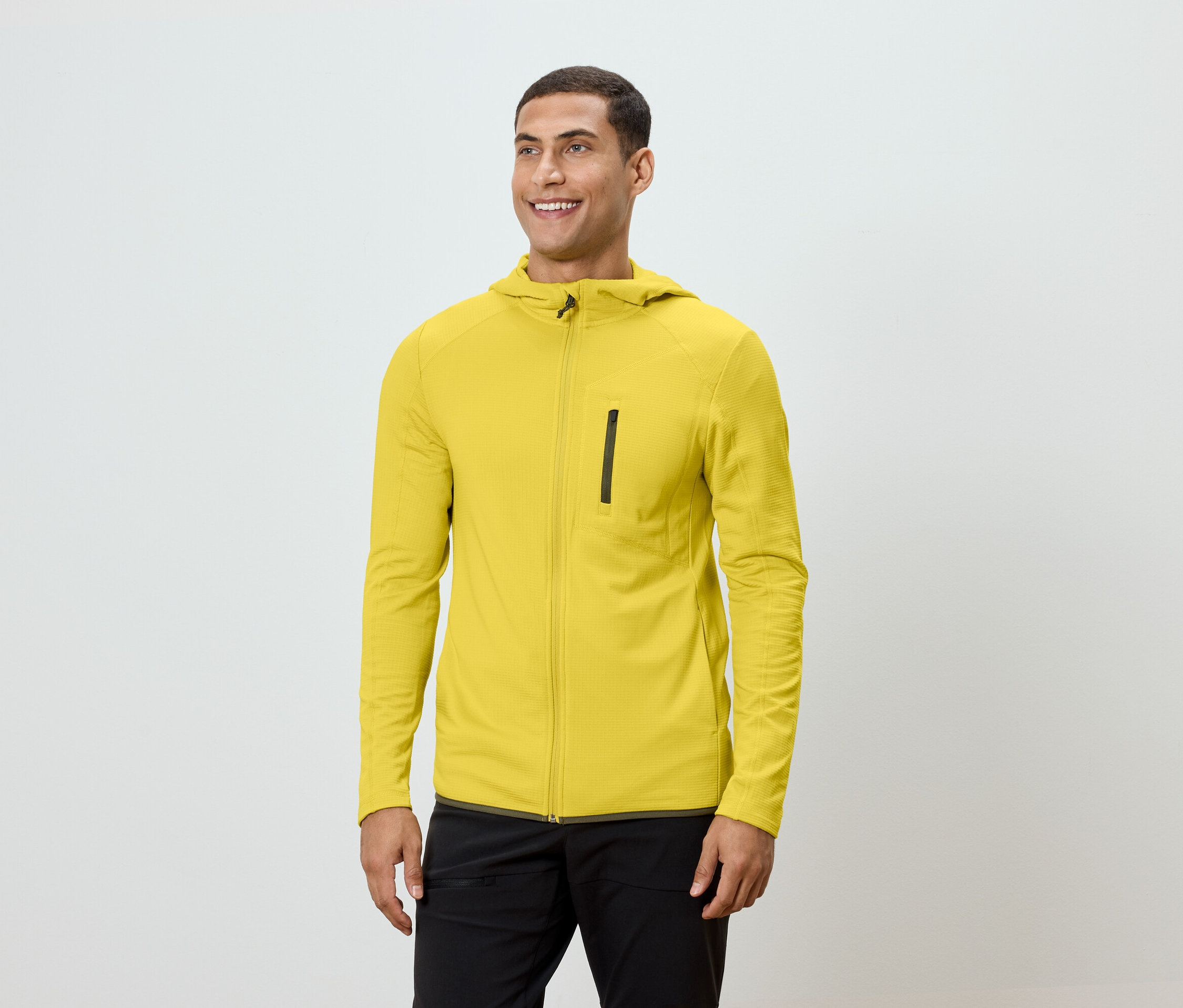 Un homme portant un sweat à capuche jaune et un pantalon noir.