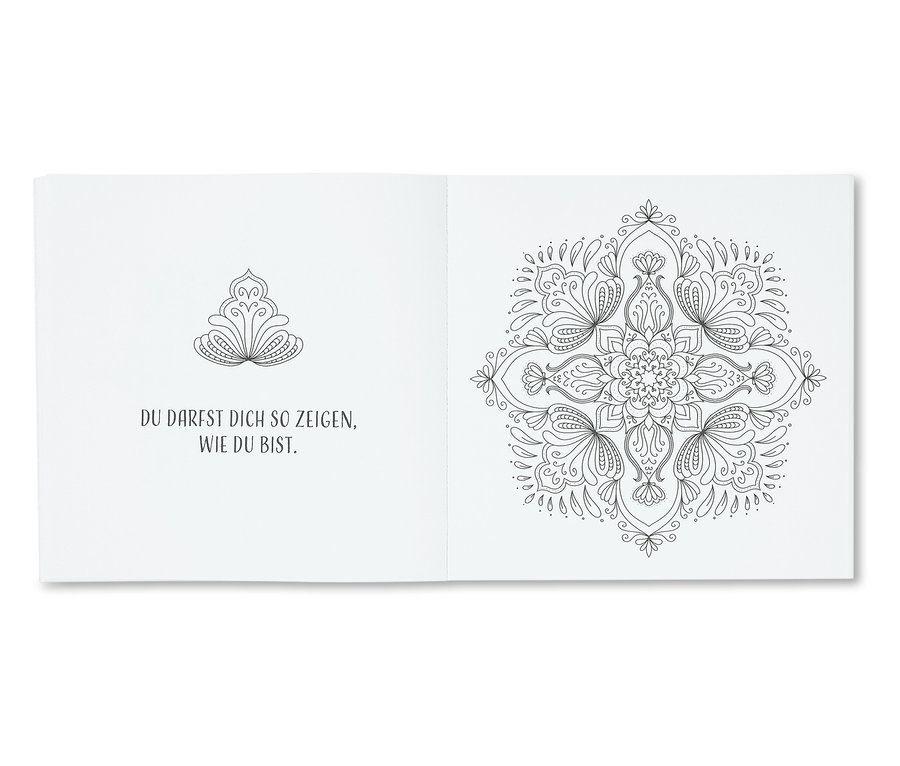 Un livre ouvert avec des mandalas floraux en noir et blanc et du texte.