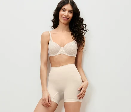 Une femme pose en sous-vêtements et short gainant.