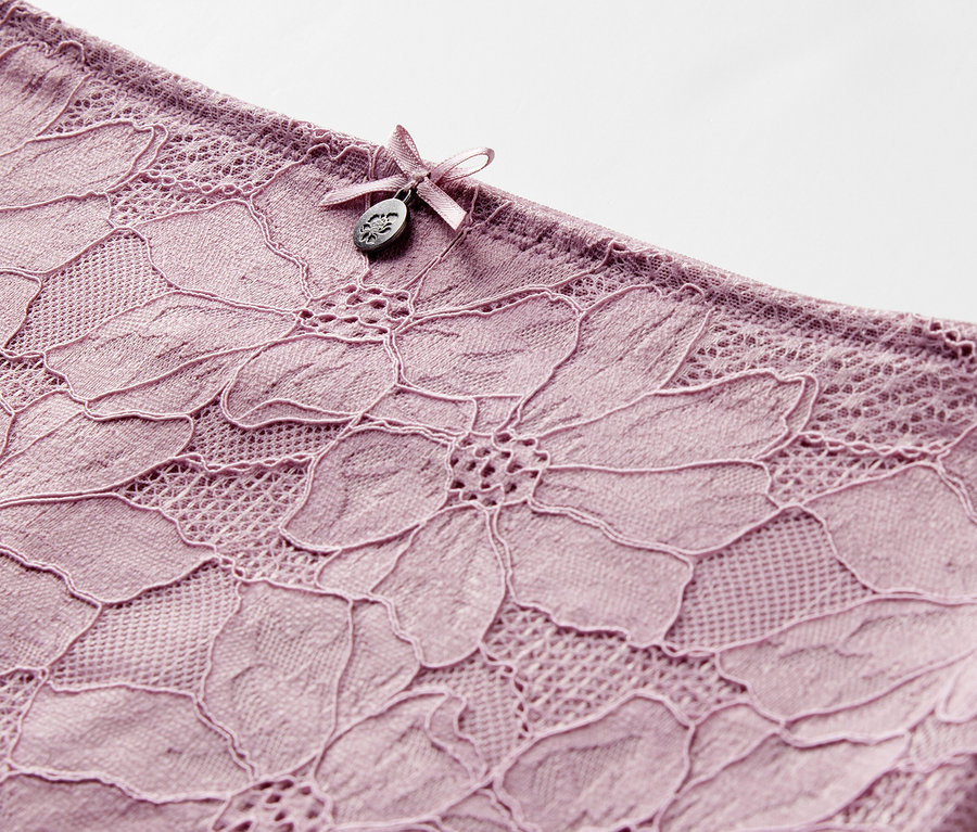 Détail d'une culotte taille haute « light-shaping », mauve, avec dentelle florale et nœud.