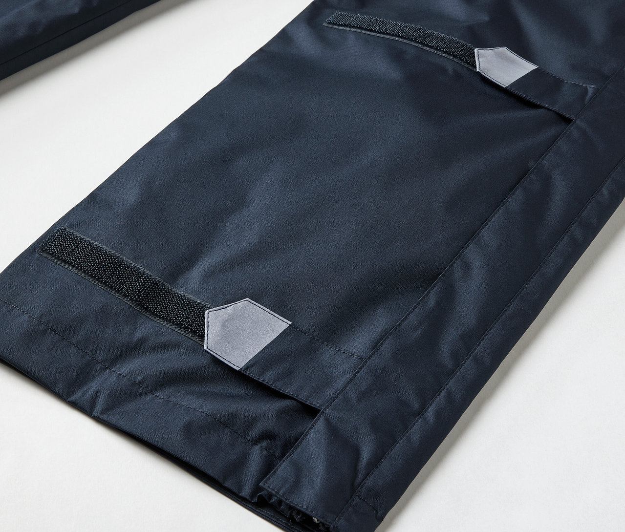 Gros plan sur un pantalon de pluie high-tech avec fermeture éclair intégrale.