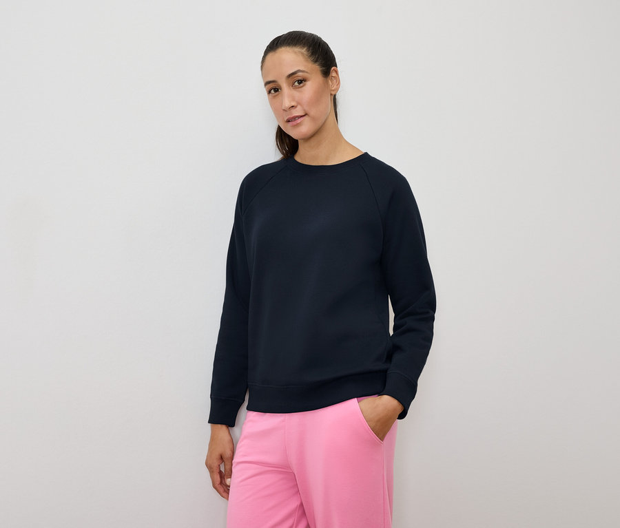 Femme portant un sweat-shirt bleu marine et un pantalon rose.