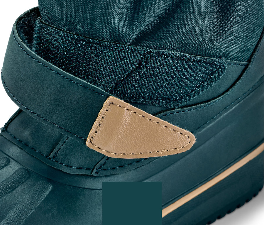 Gros plan sur une botte d'hiver vert foncé avec une sangle velcro en cuir marron.