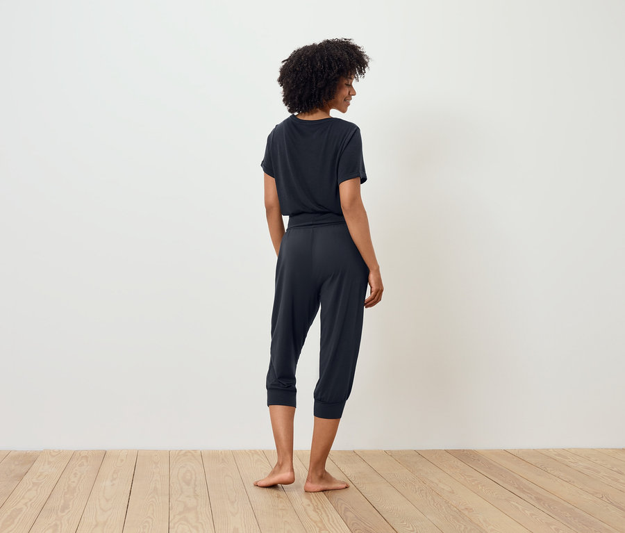 Femme en t-shirt foncé et pantalon trois-quarts, dos à la caméra.