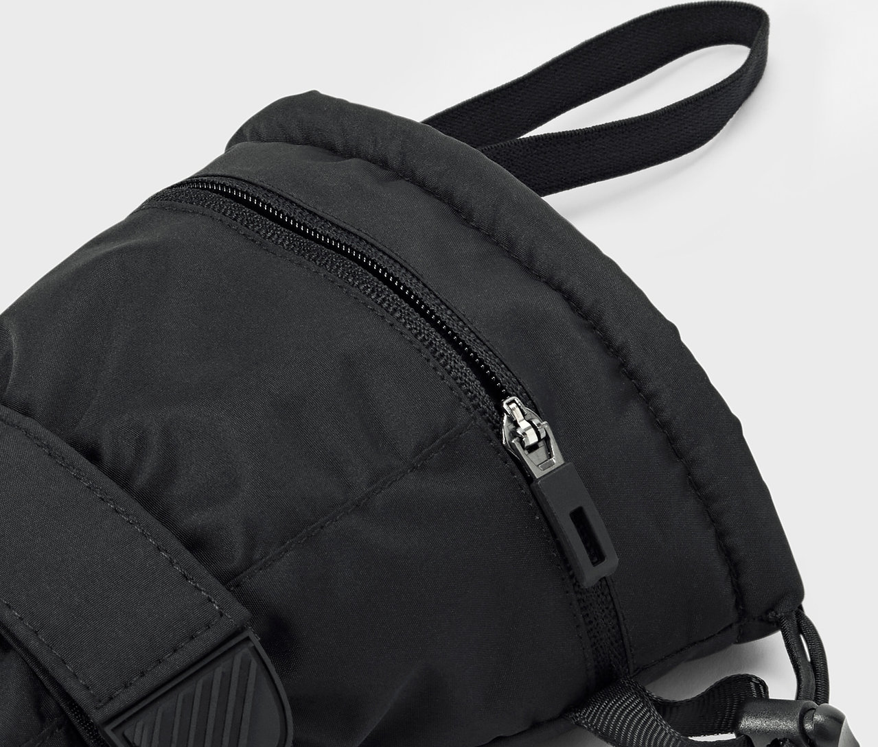 Gros plan d'un sac à dos noir avec une fermeture éclair et une sangle visible.