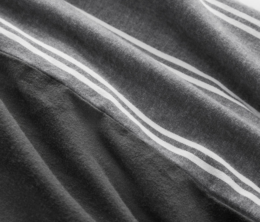 Gros plan d'un tissu gris avec trois bandes blanches.