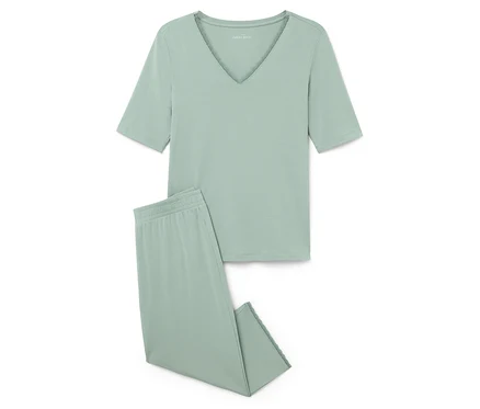 Un pyjama vert clair composé d'un haut à manches courtes et d'un pantalon posé sur un fond blanc.
