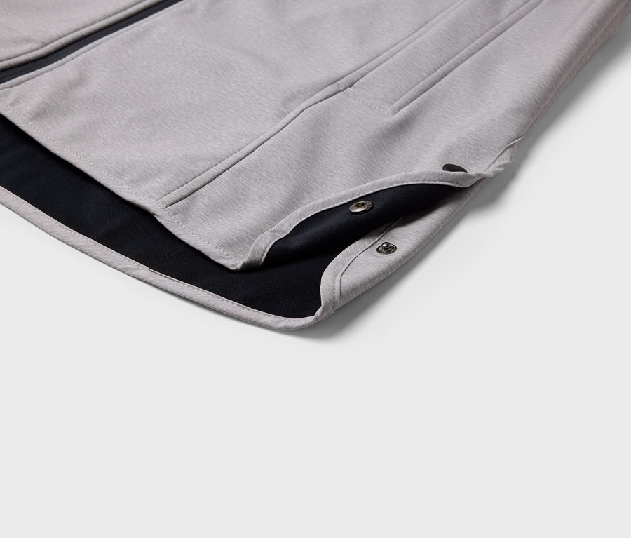Gros plan sur une veste grise avec une doublure noire et des boutons-pression.