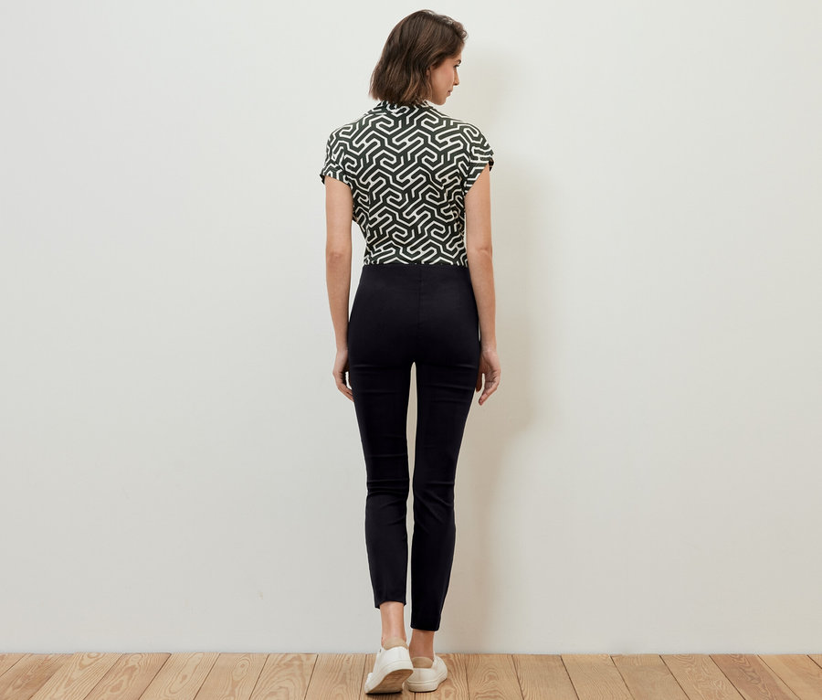Une femme, vue de dos, porte un pantalon stretch noir.