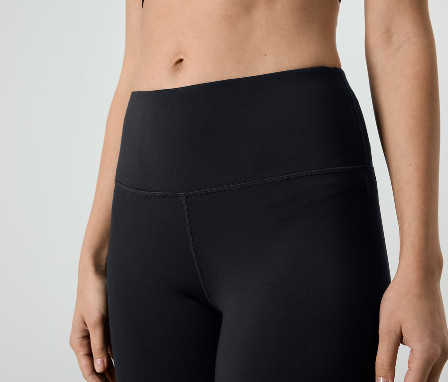 Gros plan d'une femme portant un legging noir et un haut de sport.