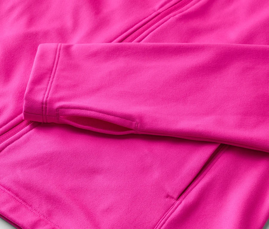 Gros plan d'une veste polaire rose avec fermeture éclair et trous pour les pouces sur la manche.