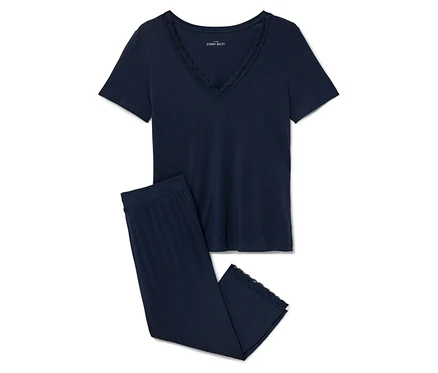 Un pyjama bleu marine avec des finitions en dentelle posé sur un fond blanc.