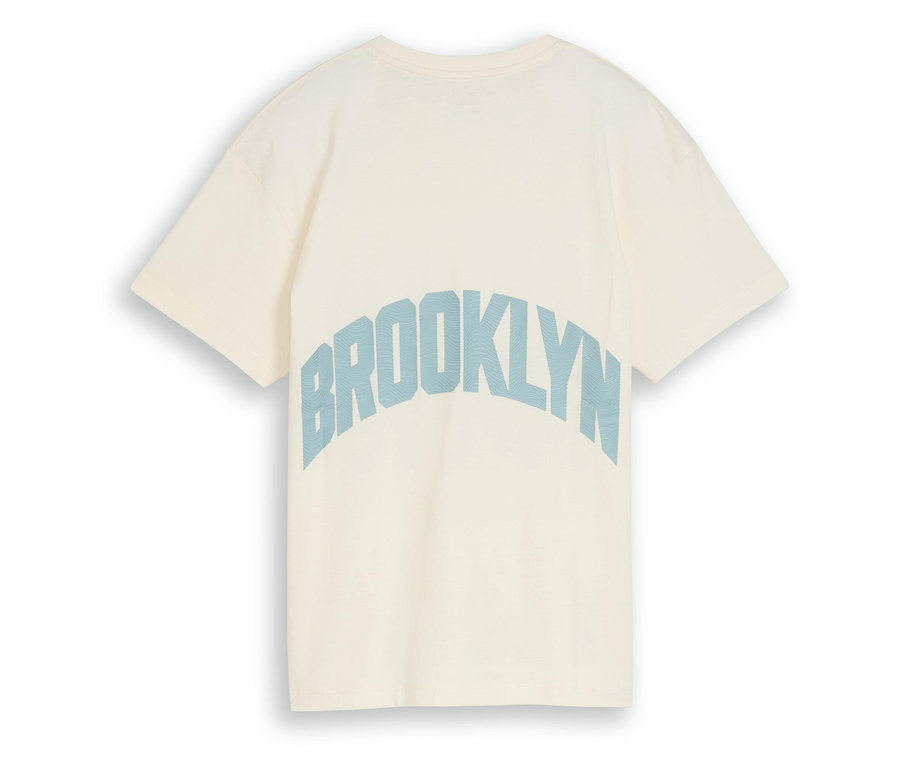 Gros plan d'un t-shirt crème avec l'inscription bleue "Brooklyn" au dos.