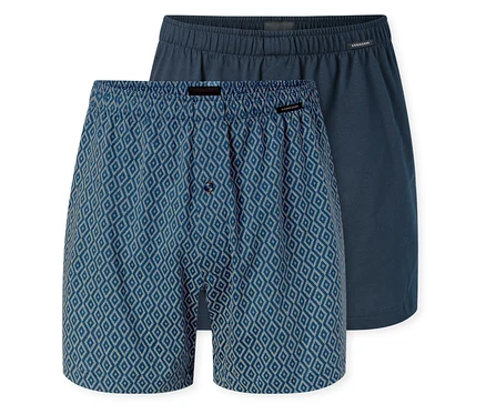 Deux boxers en jersey SCHIESSER; l'un bleu à motif losanges blancs avec une braguette boutonnée, l'autre bleu foncé uni.