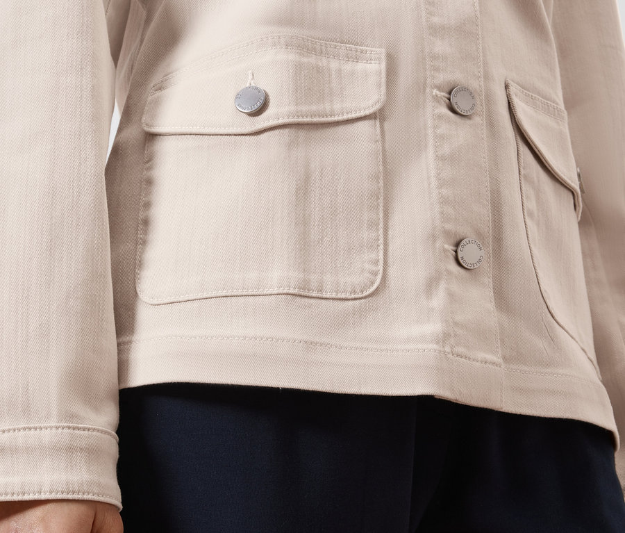 Gros plan d'une veste en jean marron clair avec des boutons argentés et des poches plaquées.