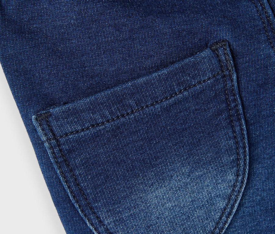 Gros plan d'un jean bleu foncé avec une poche arrière et une ceinture scintillante.
