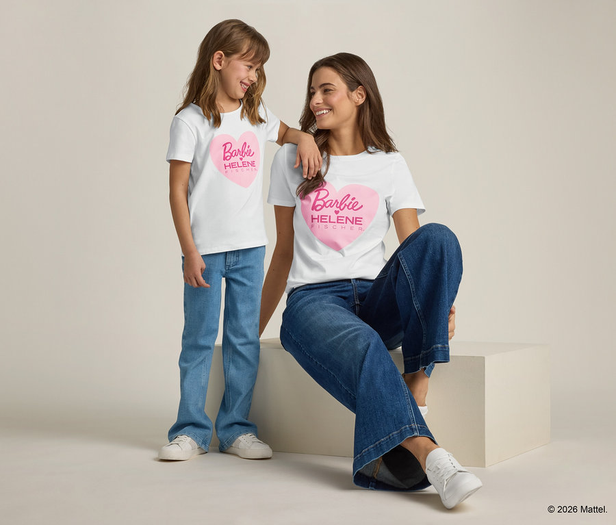 Une fille s'appuie sur l'épaule d'une femme, toutes deux portant des t-shirts blancs avec un cœur rose Barbie et des jeans.