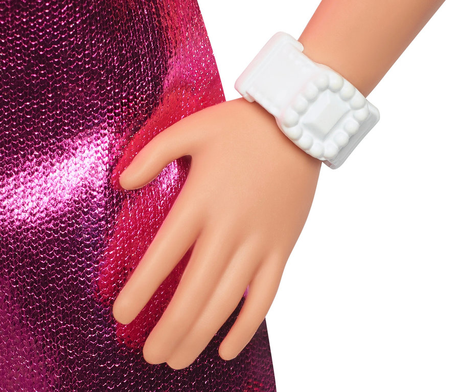 Gros plan sur la main d'une poupée portant une robe rose à paillettes et une montre-bracelet blanche.