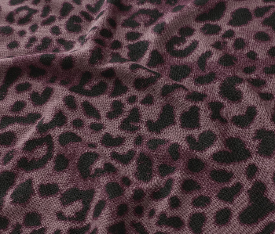 Gros plan d'un tissu avec un motif léopard noir sur un fond violet.
