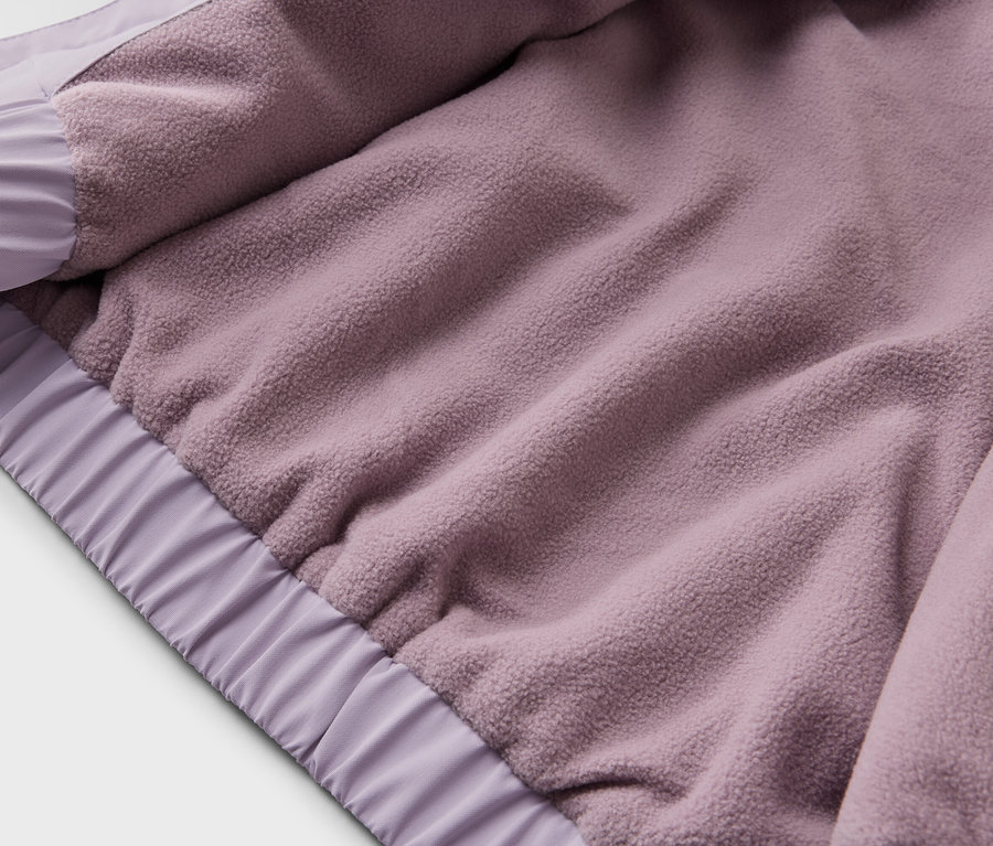 Gros plan de l'intérieur d'une veste violette avec une doublure en polaire et des poignets élastiques.