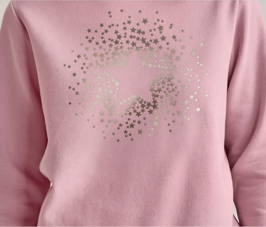 Gros plan d'un sweat-shirt rose à manches longues, orné d'un grand motif d'étoile argentée composé de nombreuses petites étoiles sur le devant.