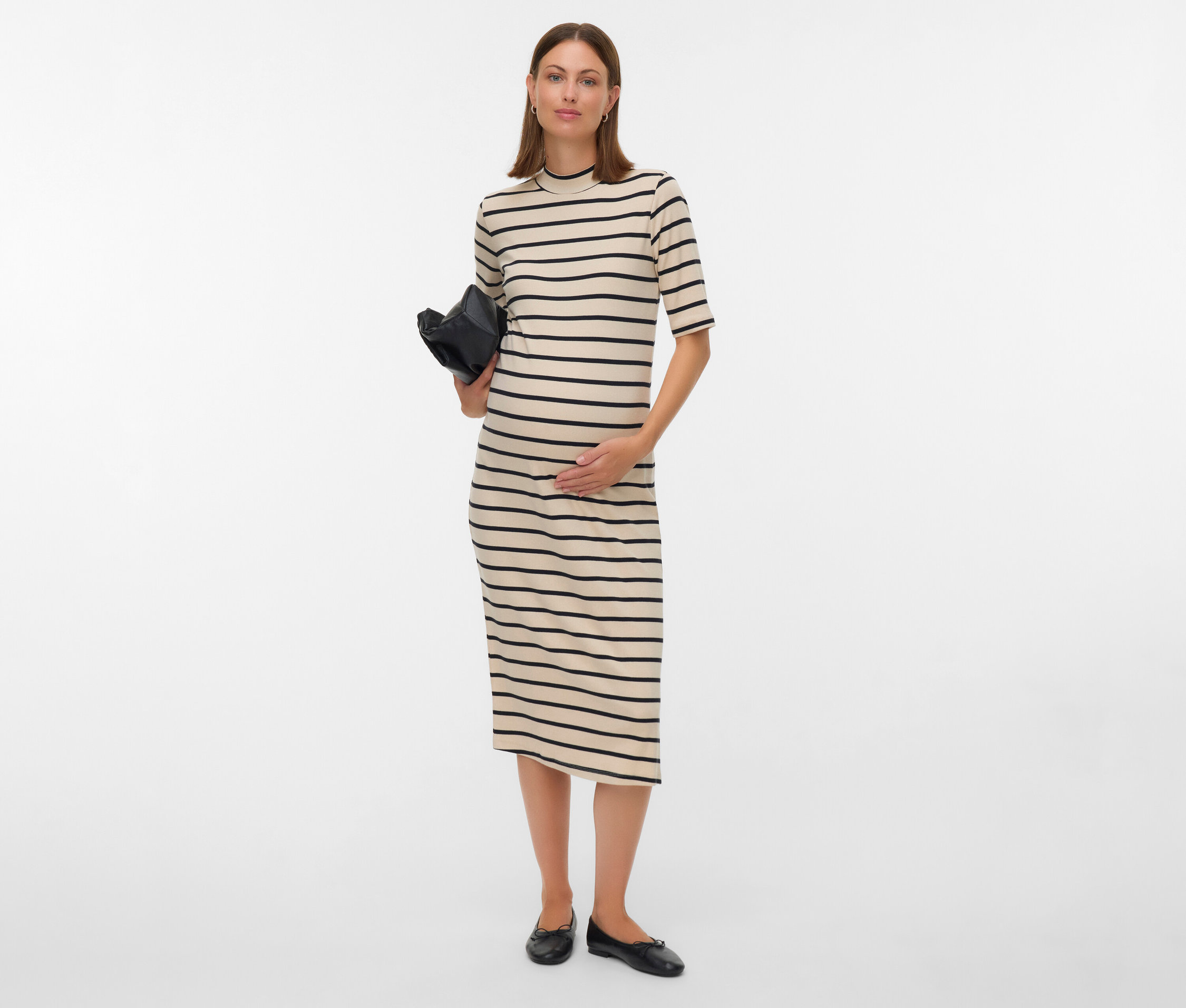 Femme enceinte en robe rayée tenant un sac noir.