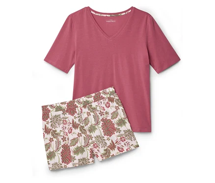 Un haut rose à manches courtes et un short à motifs floraux sont posés pliés sur une surface blanche.