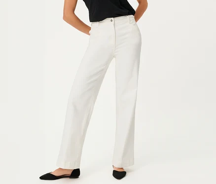 Une femme porte un jean Olsen à jambes larges et des chaussures noires sur fond blanc.