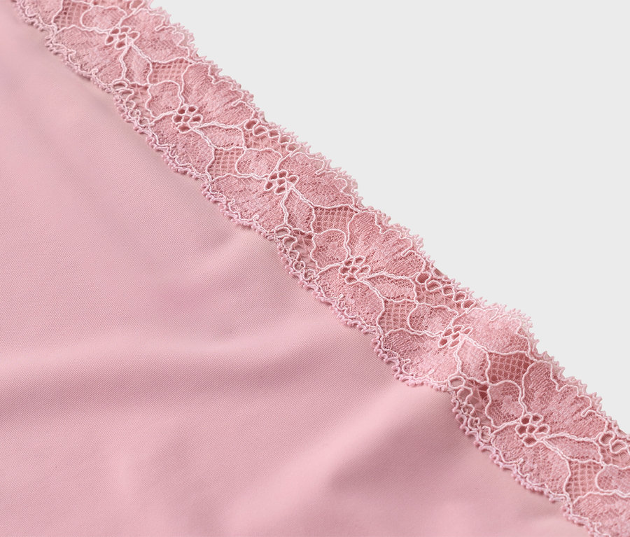 Gros plan d'un tissu rose avec de la dentelle rose délicate.